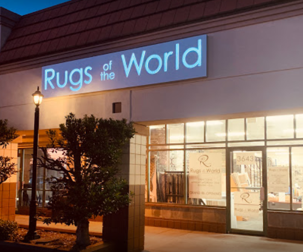 Exterior photo of Rugs of the World's storefront at night.